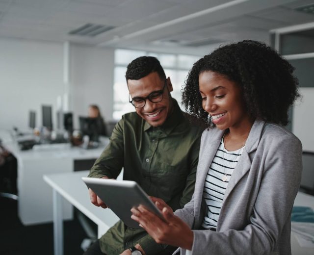 Smiling young african american professional businessman and businesswoman together working online with a digital tablet in office